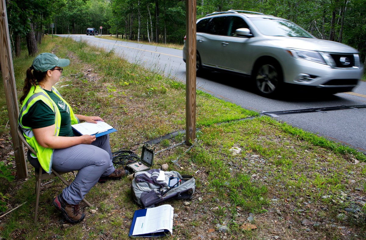 Roadside technician watches a car cross a traffic counter