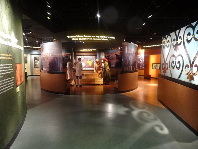 Visitor Center displays, including a burial scene at center.