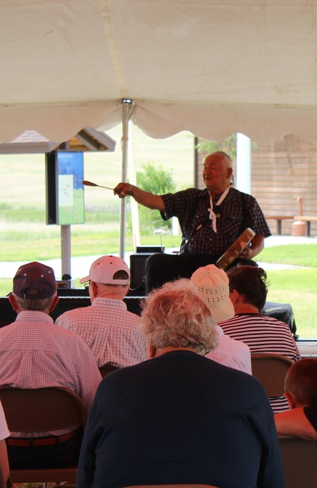 Jerome Kills Small with his drum telling stories under a tent.