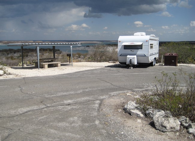 Trailer camper with picnic table, ramada, and trash receptacles at Governors Landing campground.