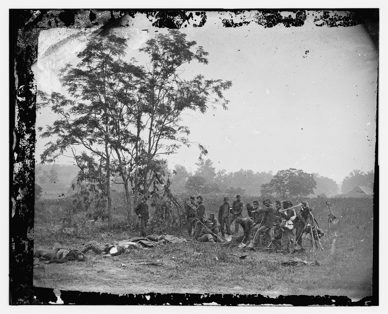 soldiers pose for photo with shovels used in digging graves