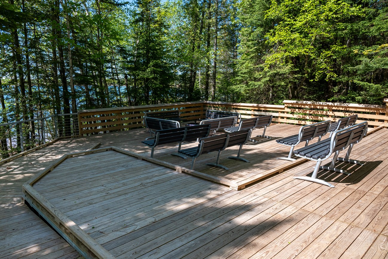 Photograph of wooden platform with benches surrounded by trees.