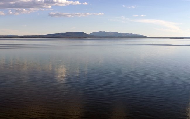 Figure 2 Photo looking out towards a lake. The water is blue with mountains in the background.