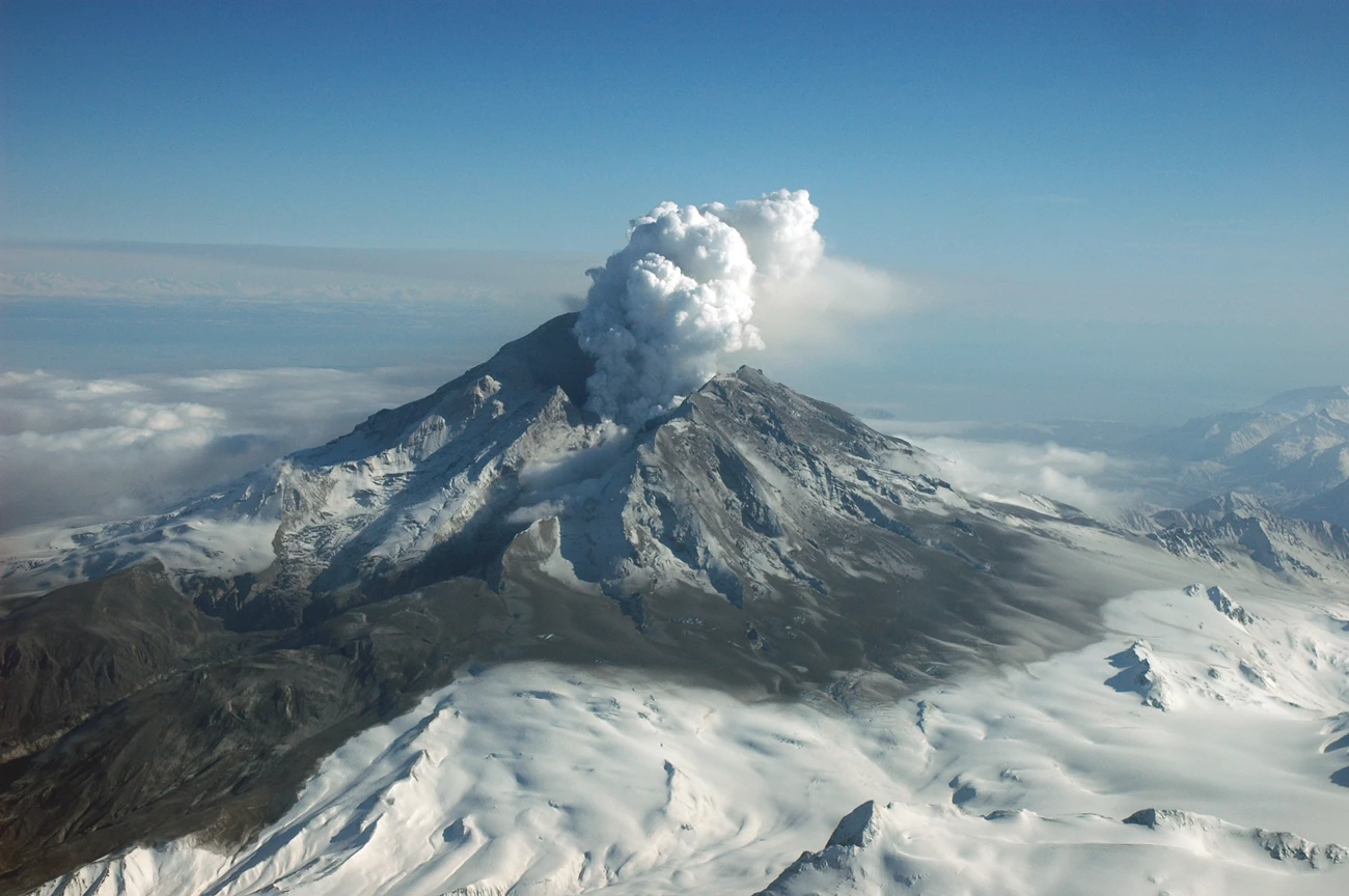 1238960115_ak231 Photo of an erupting volcanic mountain with a steam cloud above the summit crater and snow on its lower slopes