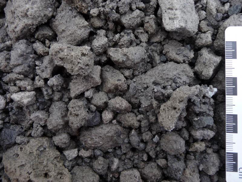 photo of blocky rocks that have small air holes, shown with a ruler for scale.