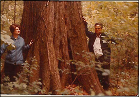 Vintage photo of two people standing next to large tree truck