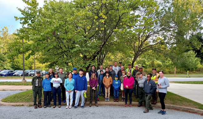2022 NPLD VAFO Group Photo A group of smiling people stand outside, under trees in a parking lot