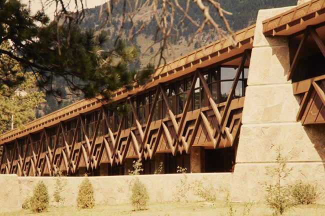 The front of a wide, low building showing a repeating geometric pattern made of wood beams