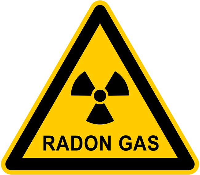 Yellow triangle with a black outline. Inside is a radioactive icon, shaped like a three-blade fan, and the words "Radon Gas."