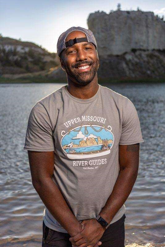 a black man smiling wearing a backwards cap