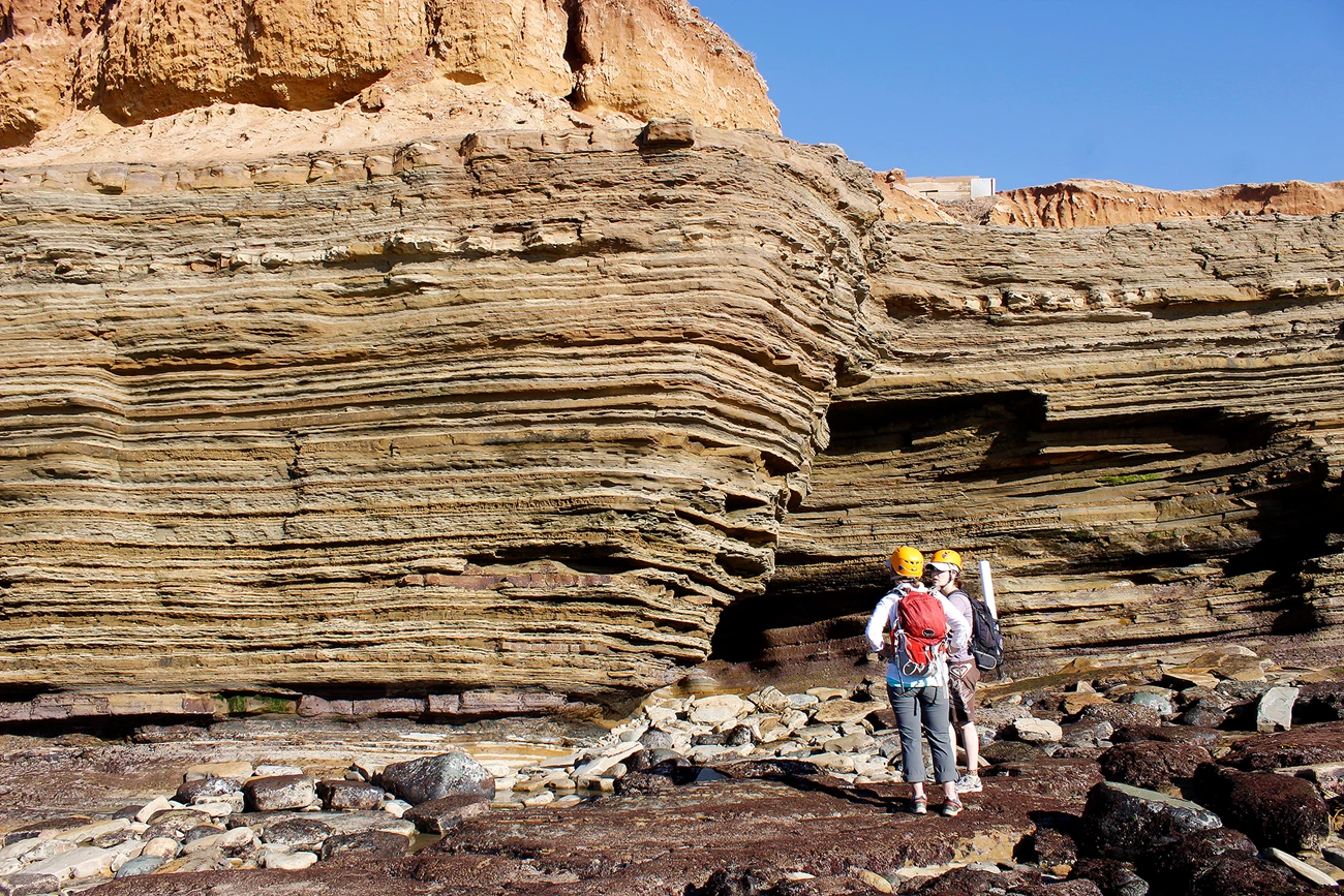 Cabrillo Formation two people waring helmets stand next to a rock formation with distinctive layering
