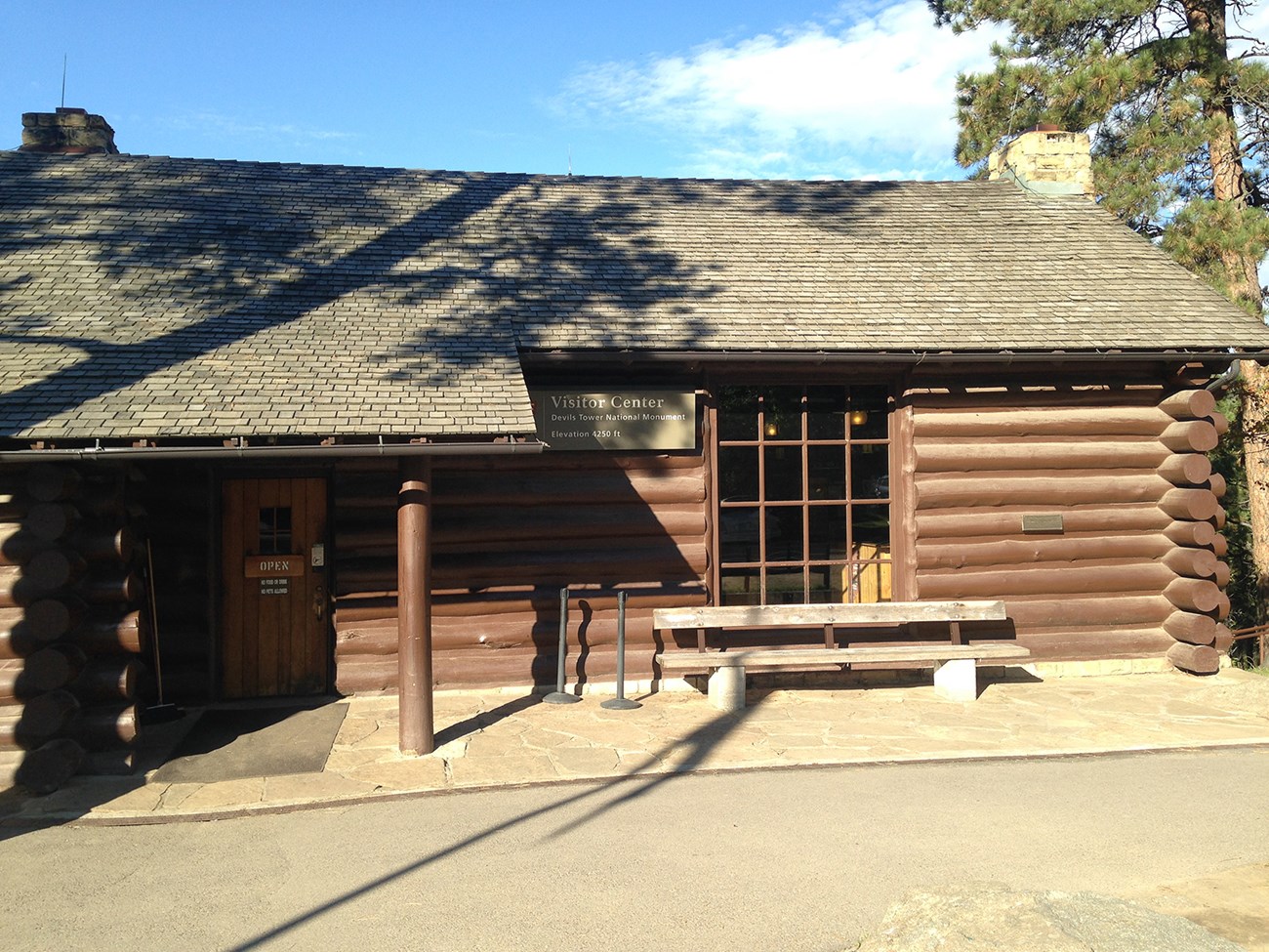 Brown log building with sign on the front that says "Visitor Center Devil's Tower National Monument."