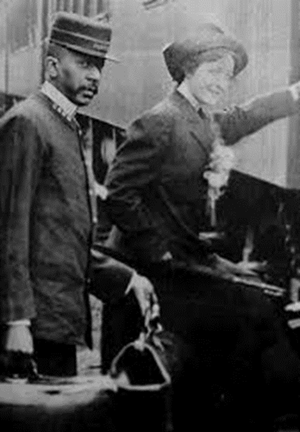 A Black porter helps a White woman onto the train.
