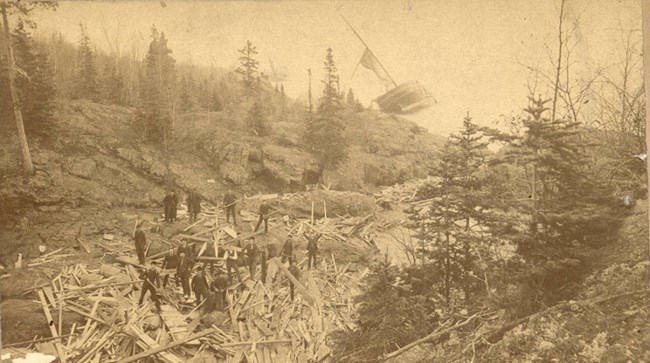 SS ALGOMA a field of boards scattered amongst the Mott Island rocks, men gather to look at the rubble left of the SS Algoma