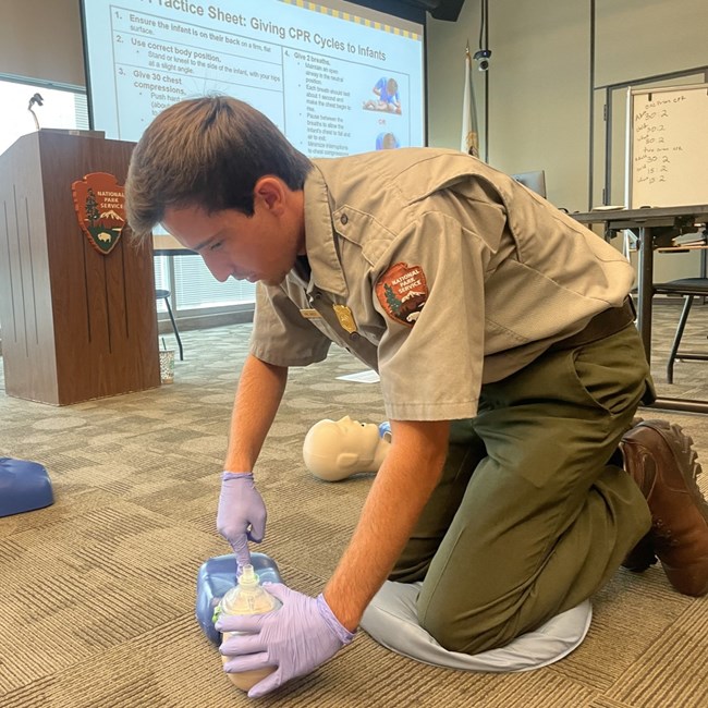 man leaning over CPR mannequin