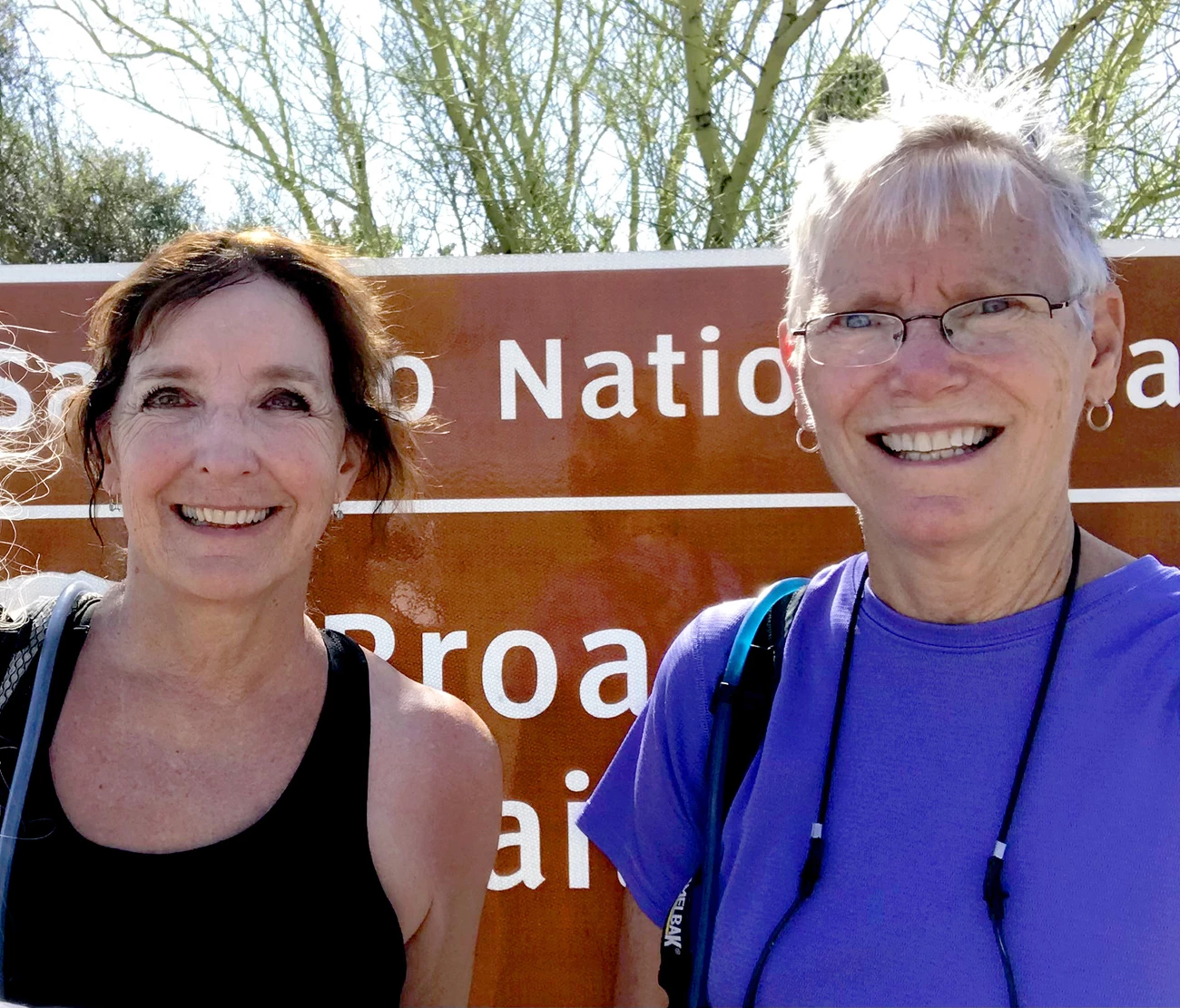 Linda White and Vivian Hutchins Two smiling women stand in front of a national park sign