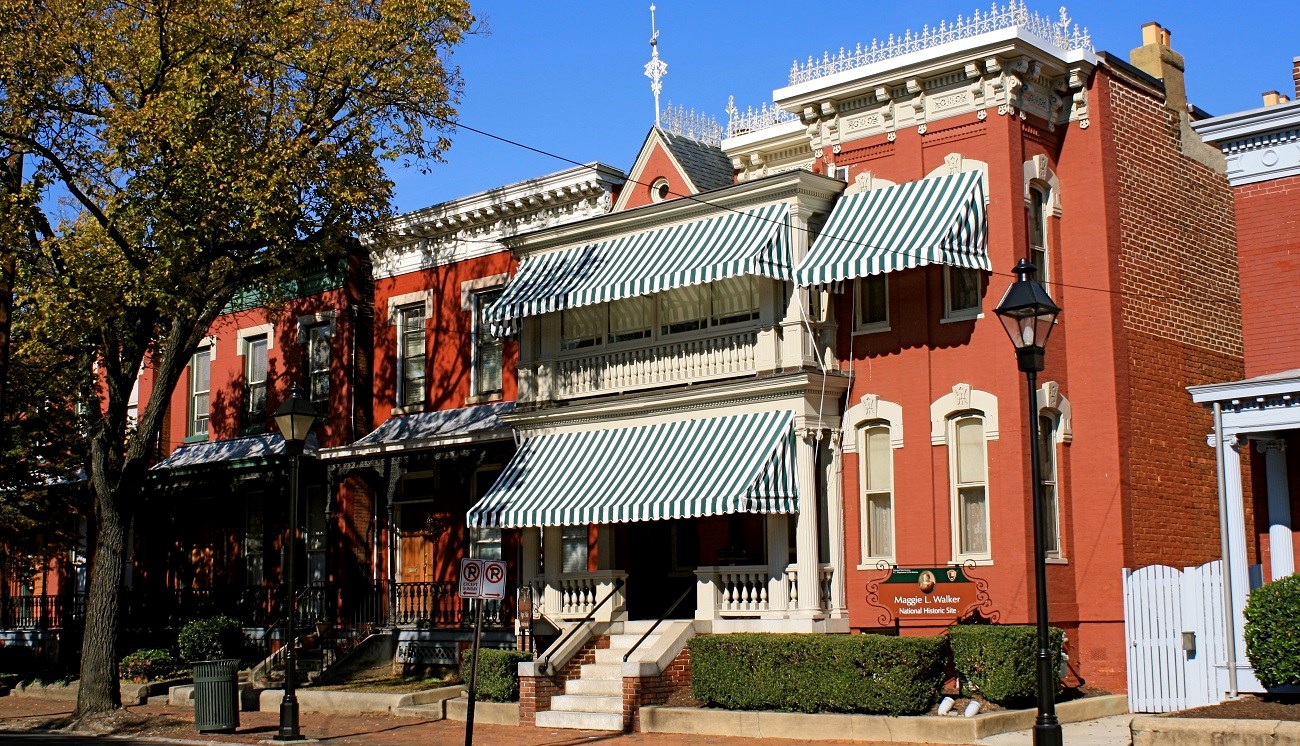 Two-story red brick townhouses with prominent green and white-striped awnings