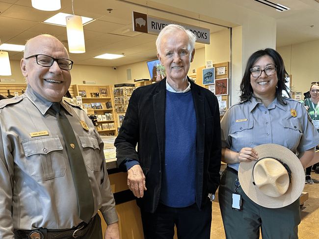 MarkKarlaandbobkerry2 Two people in park ranger uniforms pose with a man in a visitors center