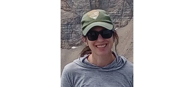 Horner outside in the mountains in a gray shirt and National Park Service ball cap.