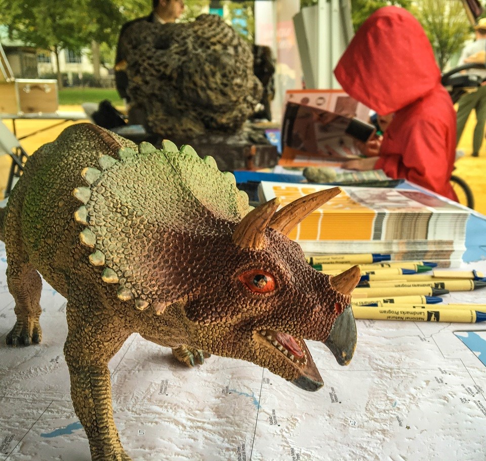 NAMA National Fossil Day NPS Victoria Stauffenberg Triceratops toy in front of a kid filling in a Junior Ranger book