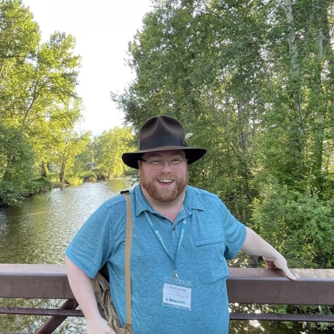 man stands on a bridge over a stream