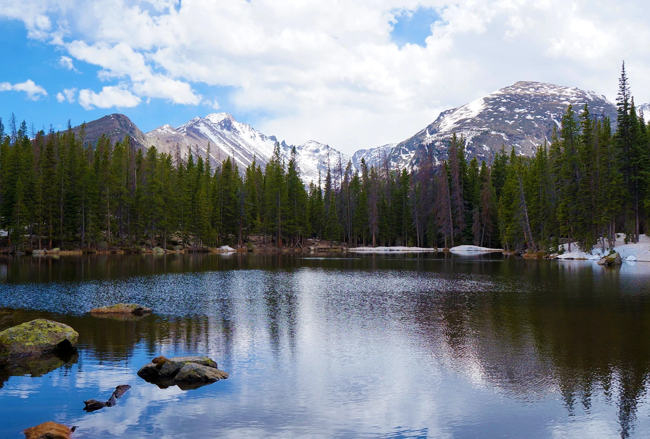 Nymph Lake A lake surrounded by snow-capped peaks and evergreen trees.