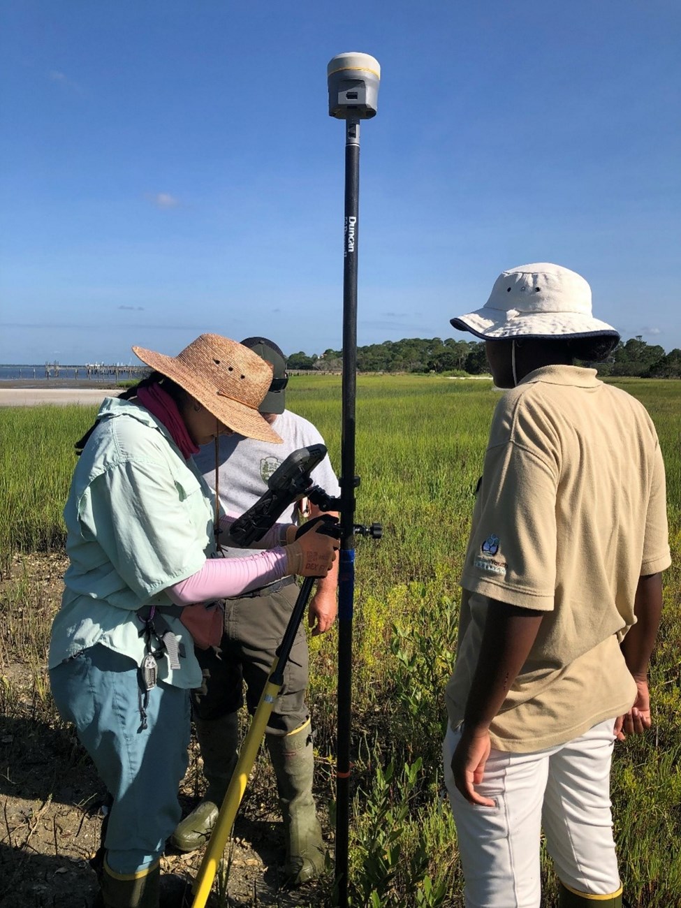 3 people marking point in marsh