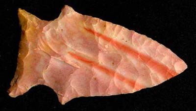 Arrowhead A flaked arrowhead in various shades of orange, yellow and cream color.
