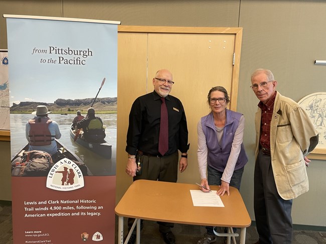 three people next to a Lewis and Clark sign