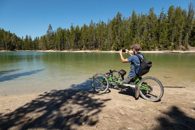 Hiker in a wheelchair taking a picture of a lake