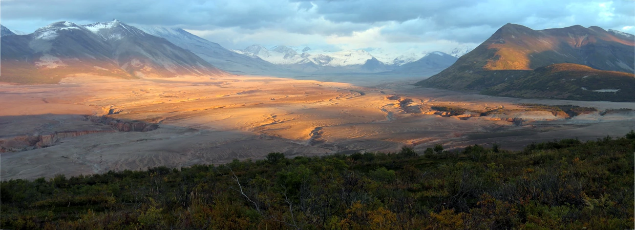 a1b6e2fa-9d87-4e0c-92cc-072318b773feOriginal photo of a volcanic landscape with large flow deposit and snow covered peaks in the distance.