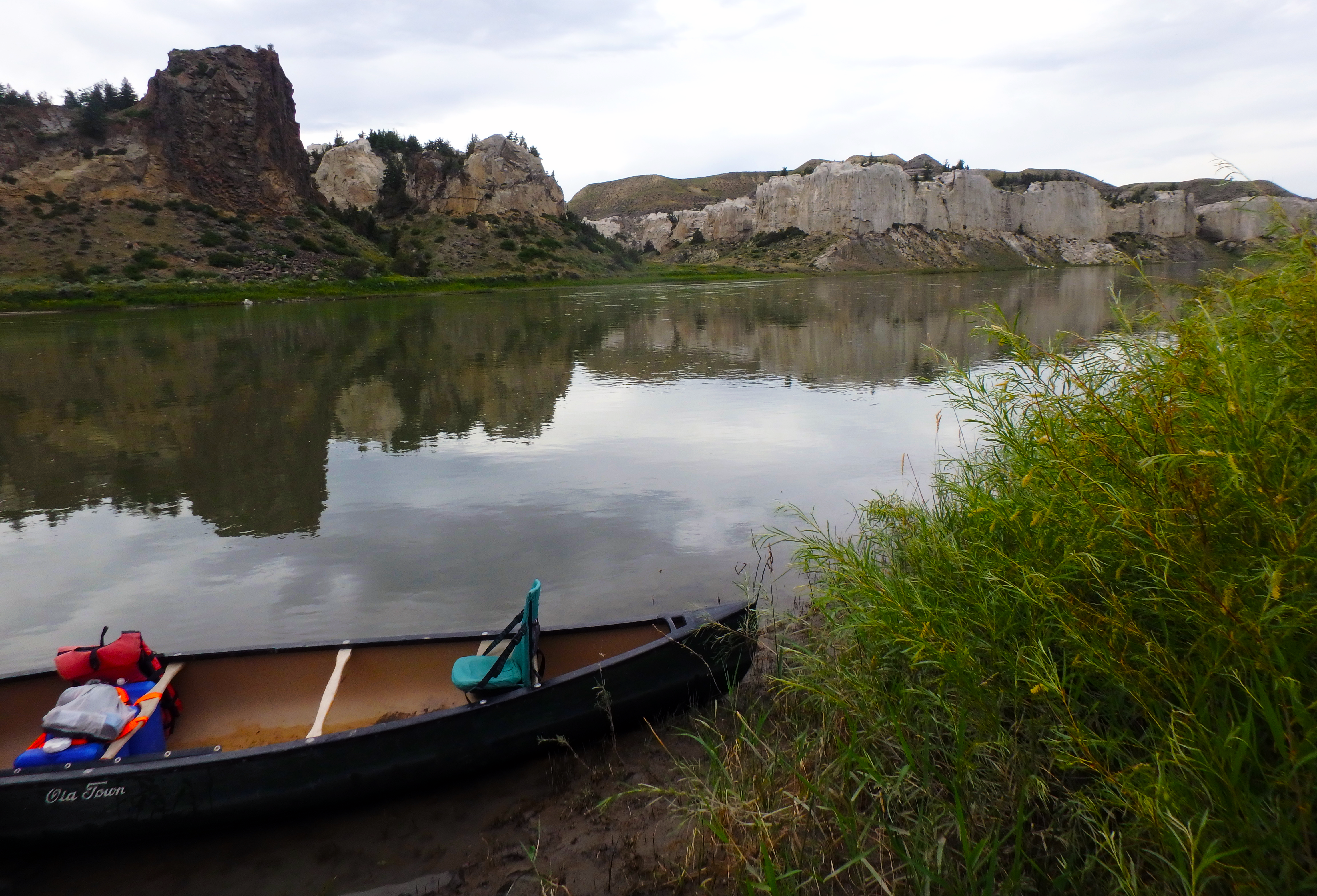 a canoe on a river with rocky cliffs in the background