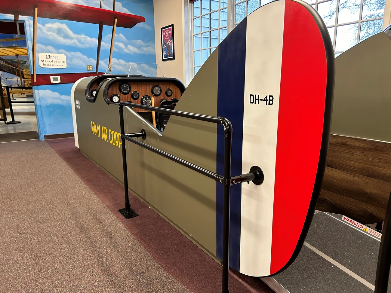 cockpit The replica DH-4 Liberty Plane cockpit in the lobby of Pearson Air Museum. It's tail is in the foreground, painted red, white, and blue with "DH-4B" painted on it. The cockpit is olive green with "Army Air Corps" painted on its side in yellow.