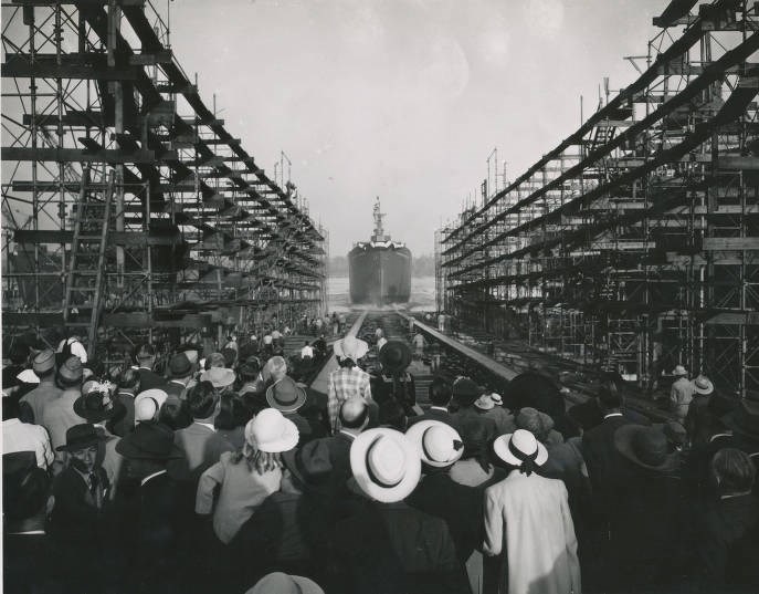 The Launching of the SS Charles Pinckney in 1942. There are dozens of people, many wearing hats, looking into the distance watching the ship launch into the ocean.