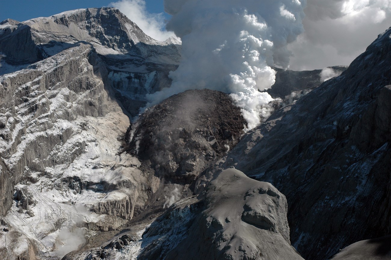 volcanic crater with dome and steam cloud