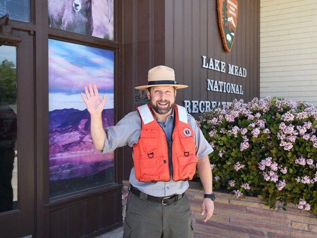 ranger smiles and waves while wearing a lifejacket