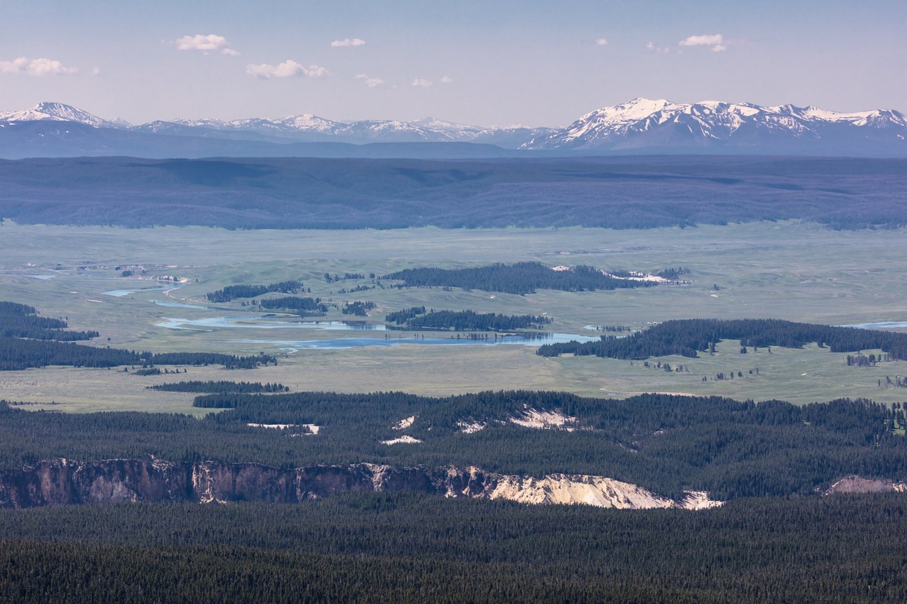 photo of a large valley with snow covered peaks in the distance