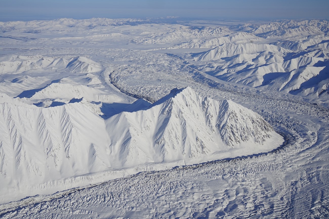 snowy glacier curving past mountains