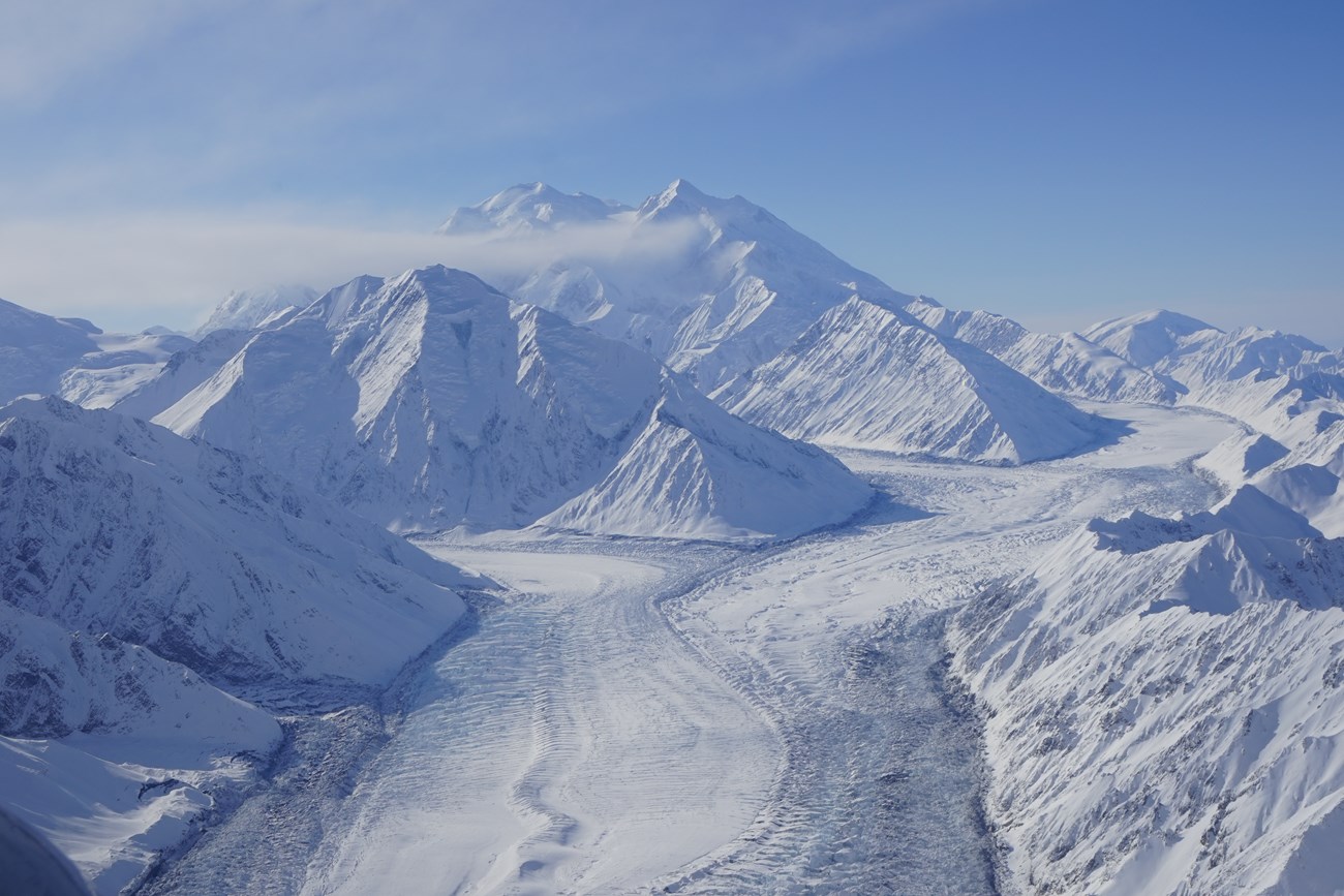 huge snowy mountain surrounded by smaller mountains and glaciers