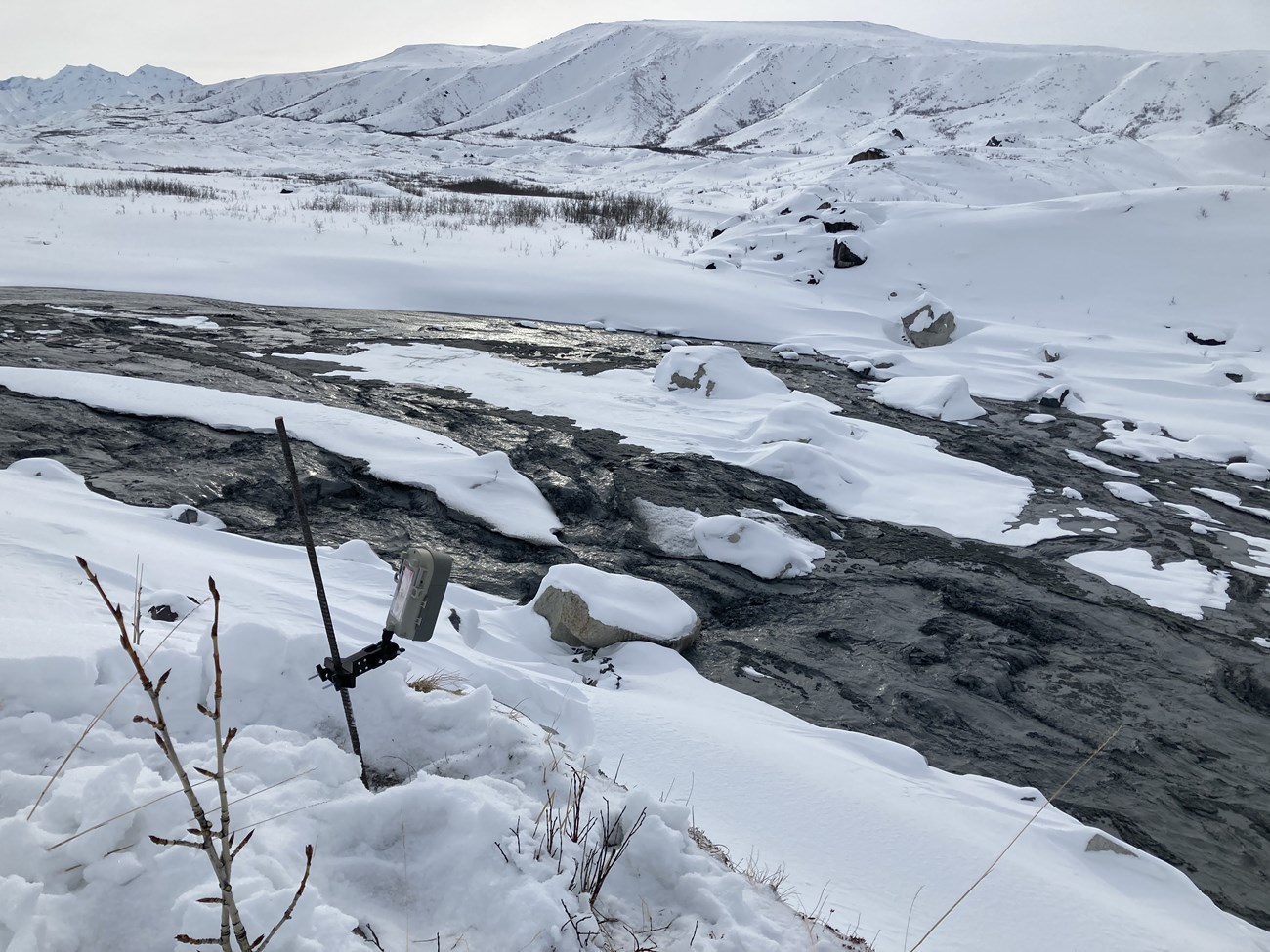 extremely dark water flowing in a snowy landscape