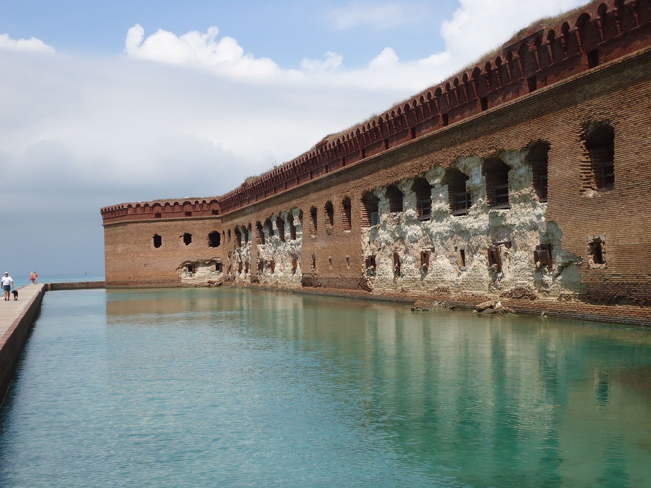 historic fort at water-level with damaged masonry wall