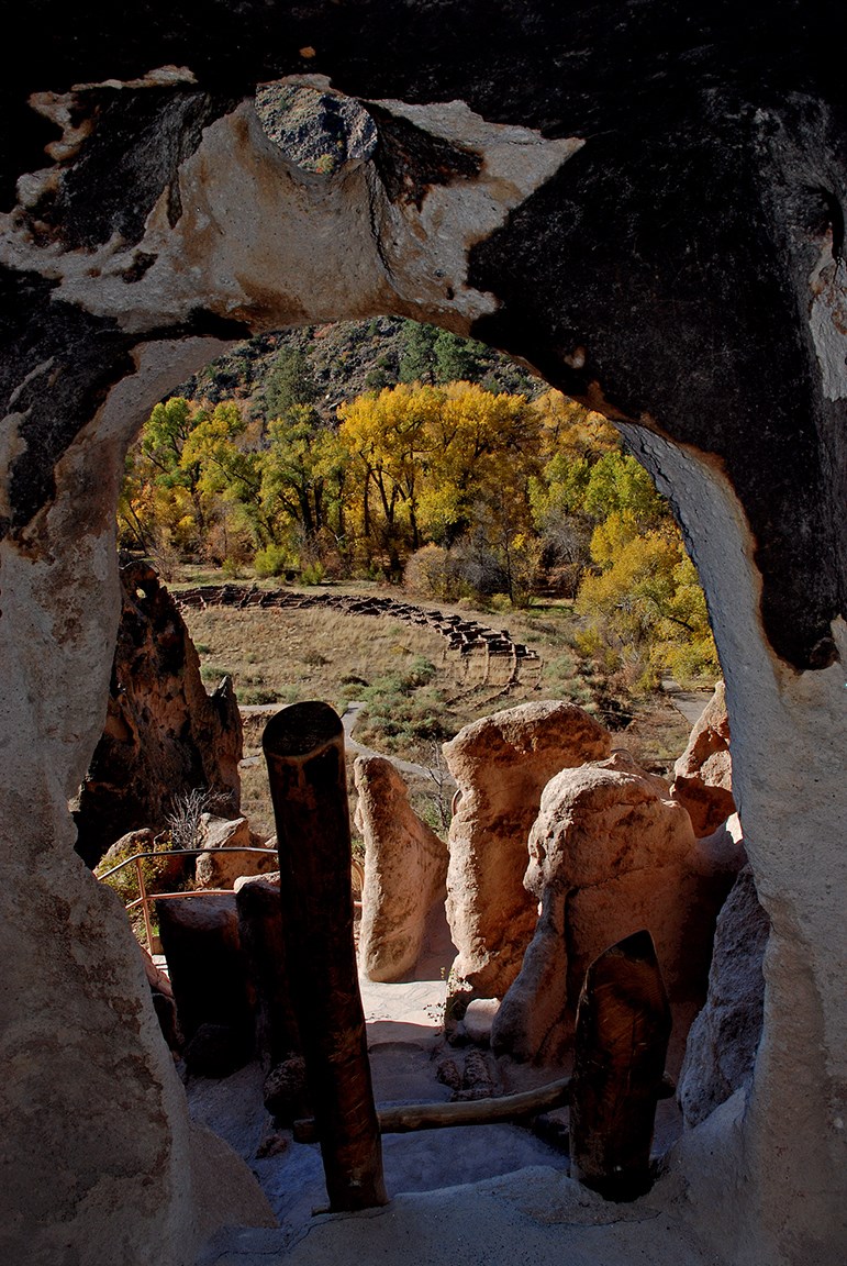 a view from a rounded doorway looking to the remnants of a large stone structure in the distance