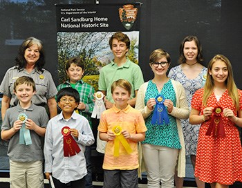 Students standing with ribbons after receiving awards for their poetry