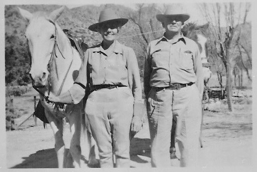 Black and white photo of a man and woman with two horses.