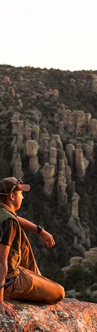 A man sits on a rock looking at the view