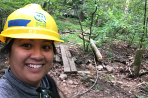 SCA Intern Raisa Barrera in wearing a yellow hardhat in the field.