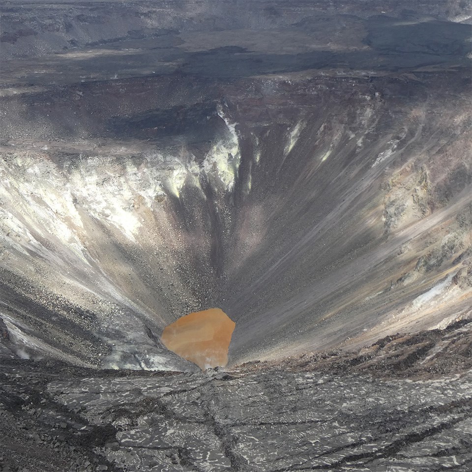 Steaming volcanic crater with small blue pool of water in the bottom