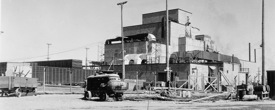 A black and white photo of a blocky building with corrugated square tubing.