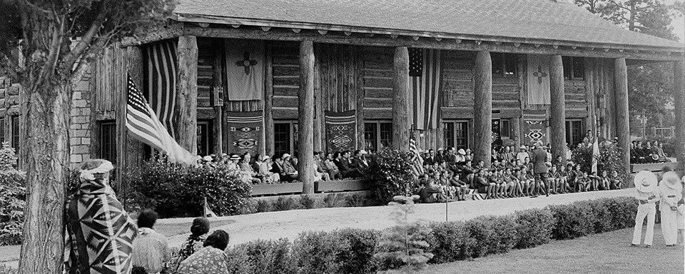 A black and white photo of a lodge made out of logs.