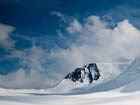 clouds brewing over a snowy mountainside